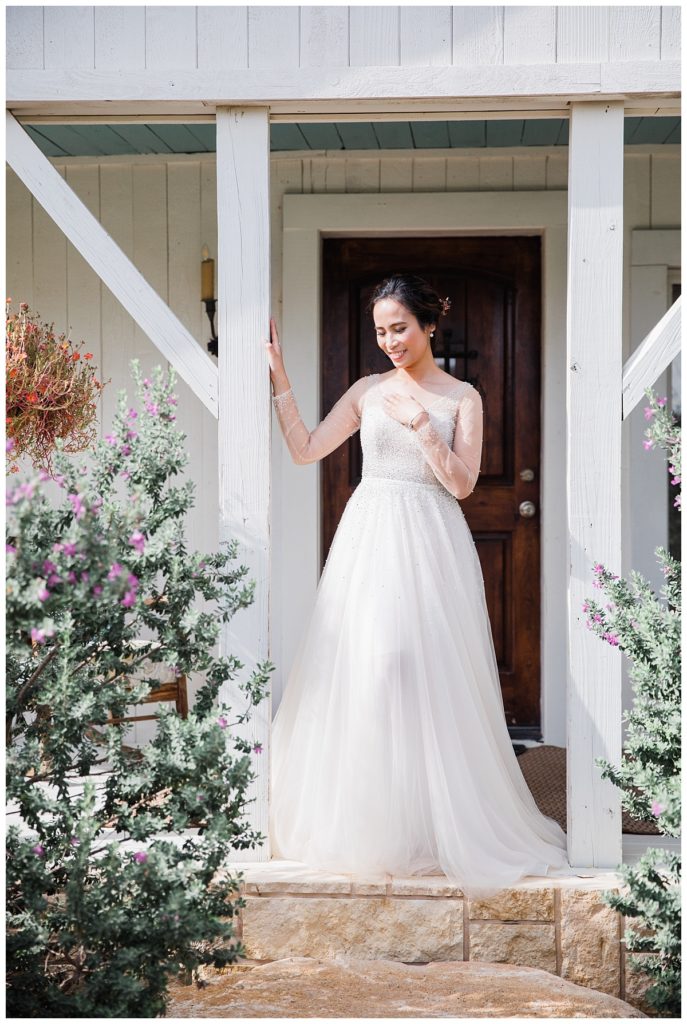 Bride in long sleeve white wedding dress standing in front of cottage bridal suite at Stonebridge wedding venue photographed by Picture Bouquet Studio. 