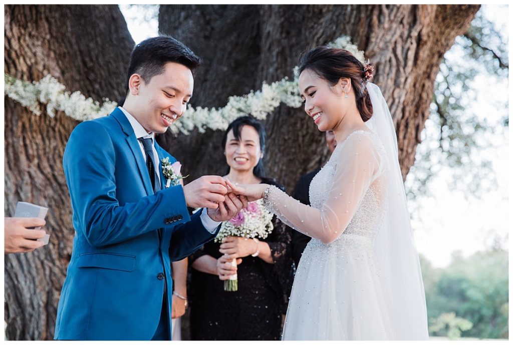 Groom exchanging ring with bride during outdoor wedding ceremony at Stonebridge wedding Venue photographed by Picture Bouquet Studio. 