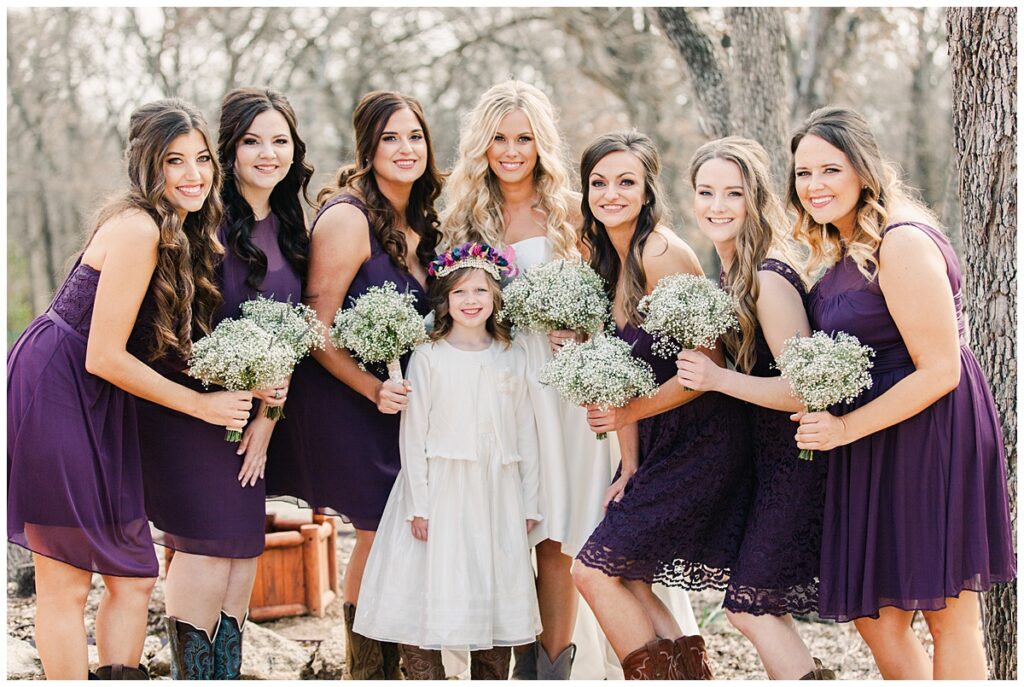 Texas styled bridesmaid poses with bride in purple bridesmaids dresses and baby's breaths bouquet for outdoor Texas styled wedding at Fort Worth Country Memorial Wedding Venue photographed by Dallas wedding photographer Jenny Bui of Picture Bouquet Studio. 