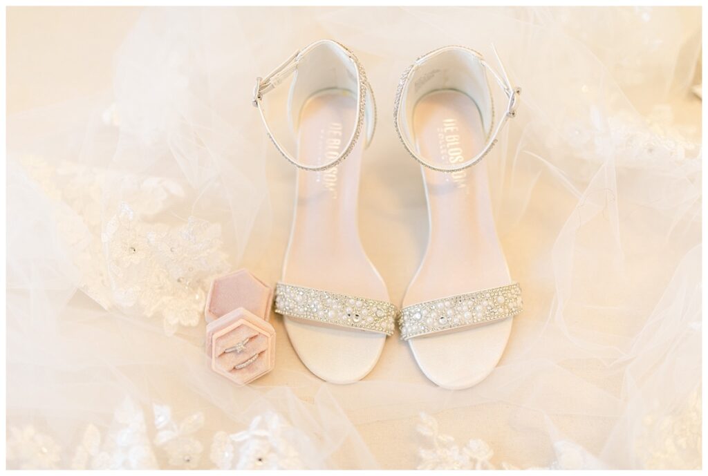 Wedding detail photo of engagement ring and wedding band, bride's shoes, and lace veil. 