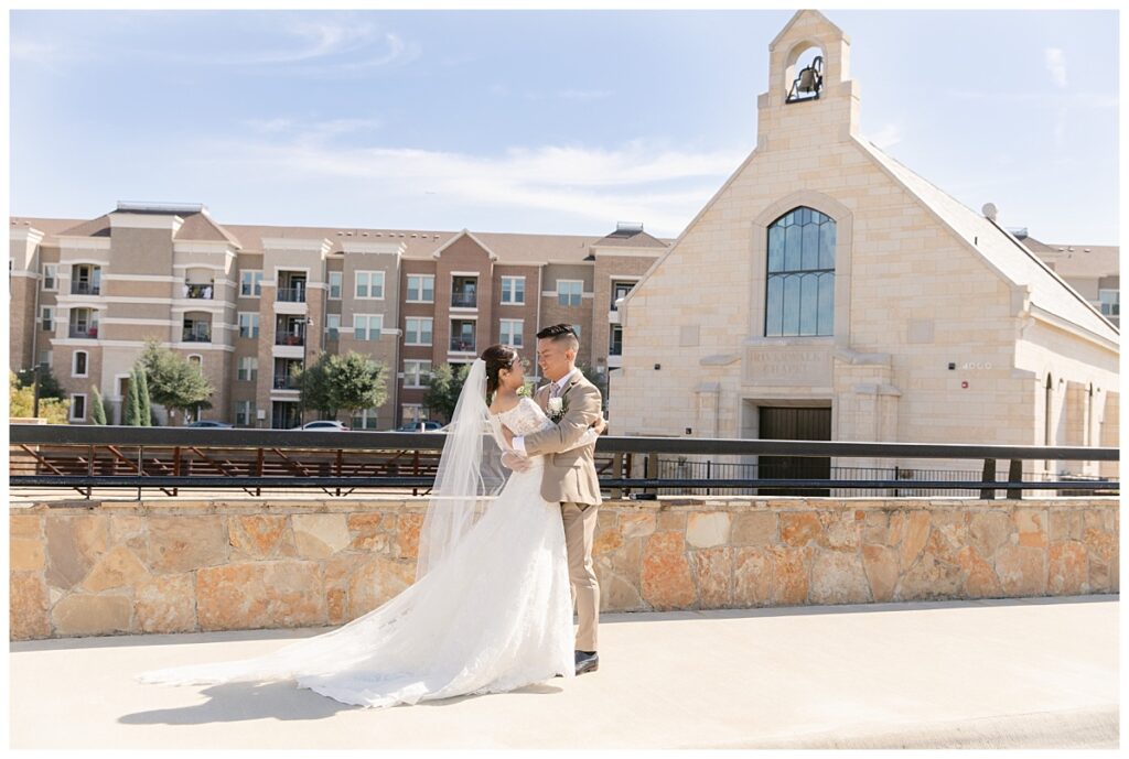 Bride in long sleeve white lace wedding gown and groom in tan suit hugs during first look at Flower Mound River Walk photographed by Dallas wedding photographer, Jenny Bui of Picture Bouquet Studio.  