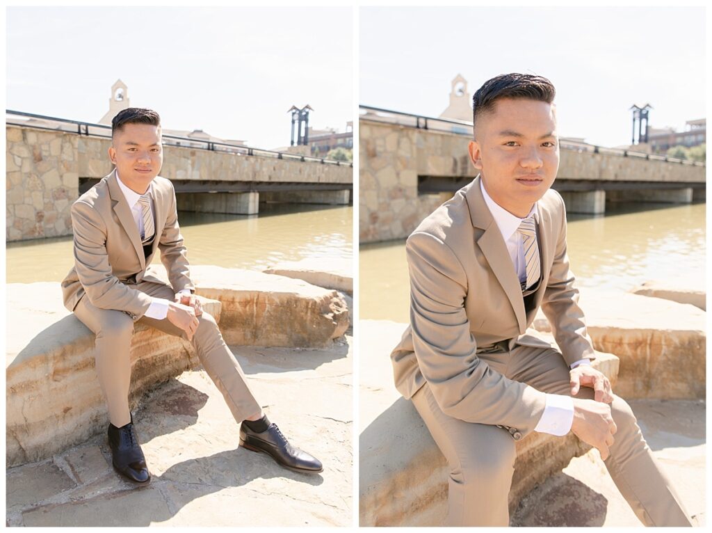 Groom in tan suit poses for portraits sitting on rock during bridal party session at Flower Mound River walk in front of rock waterfall photographed by Dallas wedding photographer, Jenny Bui of Picture Bouquet Studio. 
