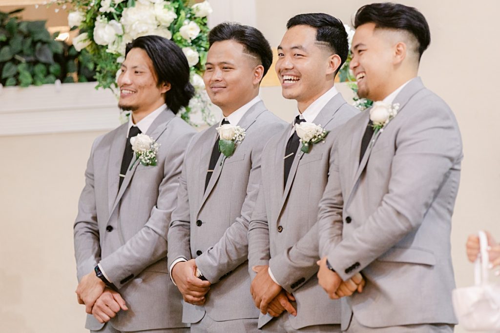 Groomsmen in grey suit laughing during wedding ceremony at Chin Revival Church photographed by Picture Bouquet Studio. 