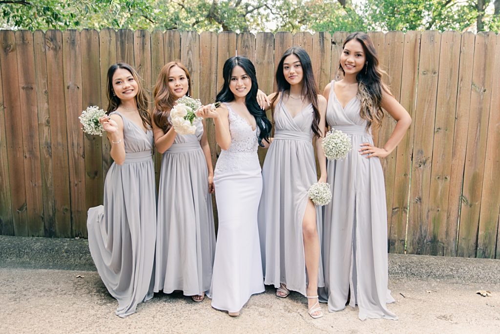 Bride with bridesmaids smiling at camera photographed at Chin Revival Church by Jenny Bui of Picture Bouquet Studio. 