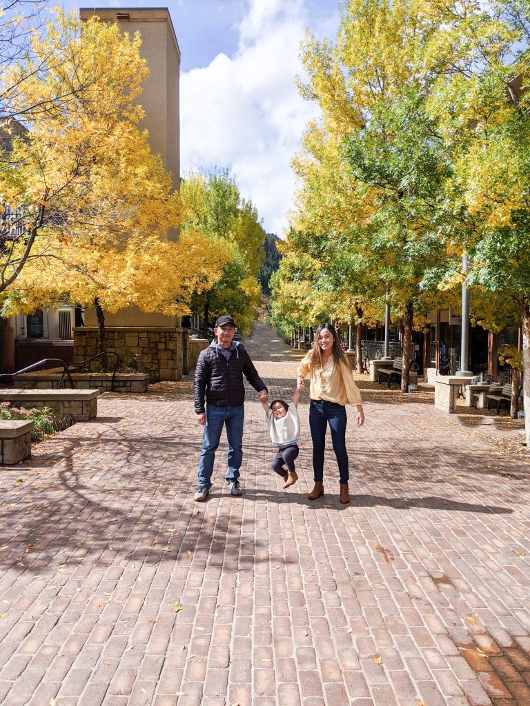 Family photo of three in pathway of yellow trees in Aspen, Colorado. 
