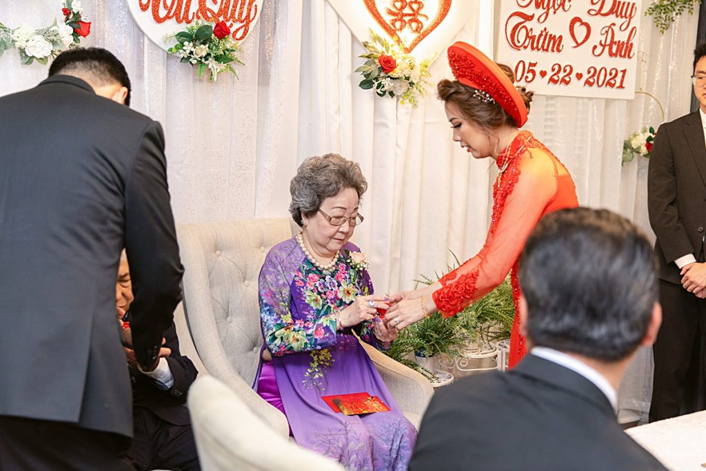 Vietnamese bride presenting tea to her grandmother for traditional Vietnamese tea ceremony photographed by Dallas Vietnamese wedding photographer Jenny Bui of Picture Bouquet Studio. 