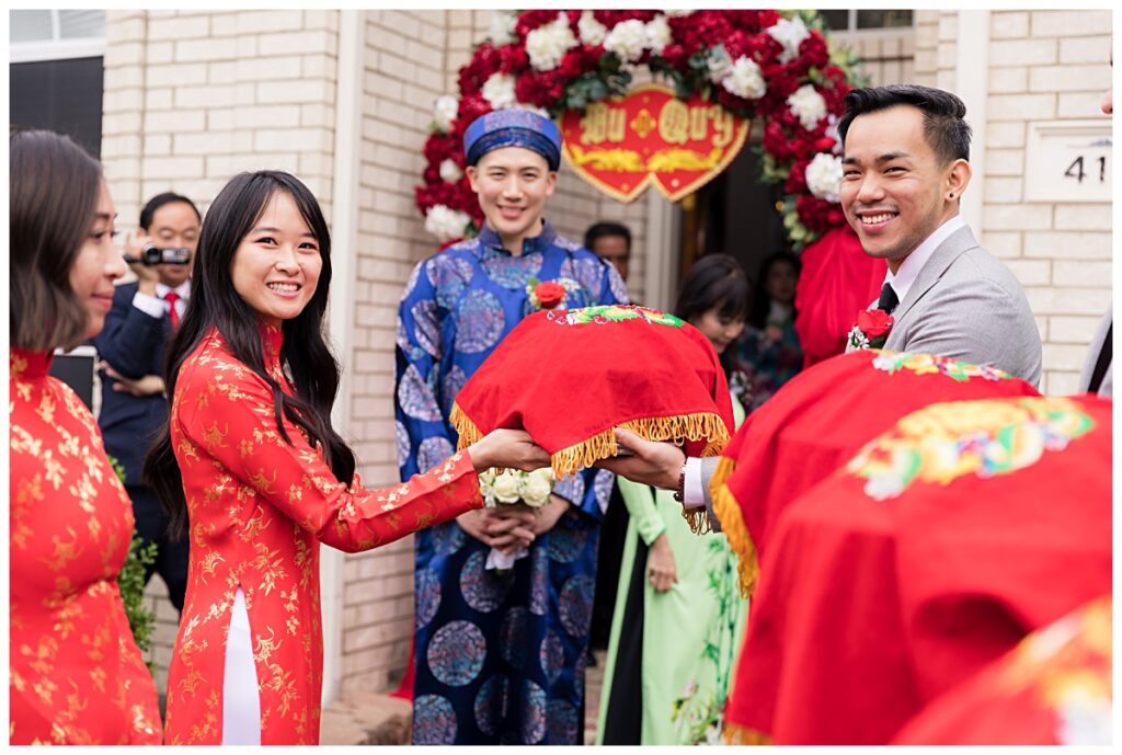 Best man handing gift tray to maid of honor for traditional Vietnamese tea ceremony photographed by Jenny Bui of Picture Bouquet Studio. 