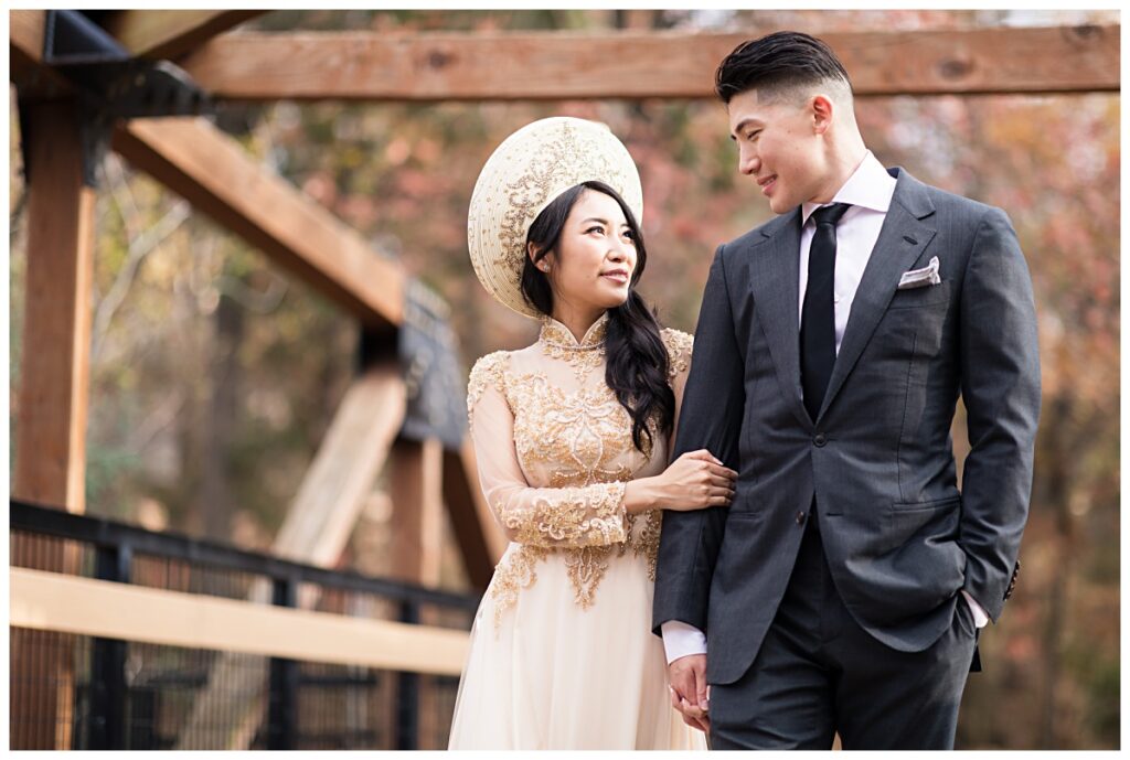 Vietnamese bride in ao dai and groom walking on bridge during Prairie creek portrait session photographed by Dallas wedding photographer Jenny Bui of Picture Bouquet Studio. 