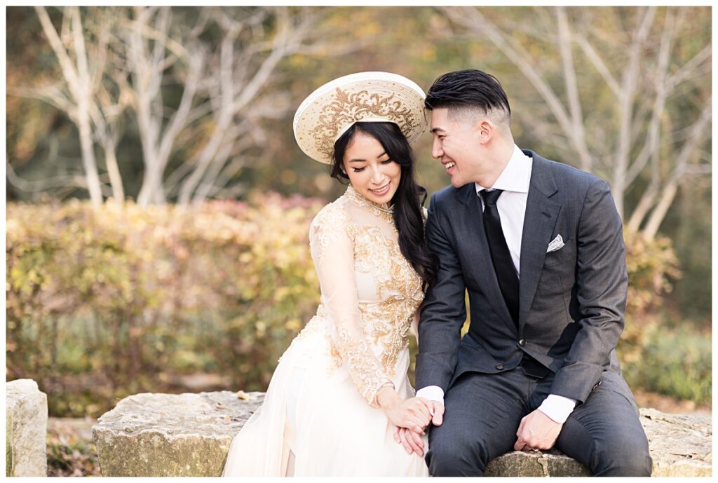 Groom in grey suit whispering in bride in yellow ao dai's ears during Prairie creek portrait session photographed by Dallas wedding photographer Jenny Bui of Picture Bouquet Studio. 