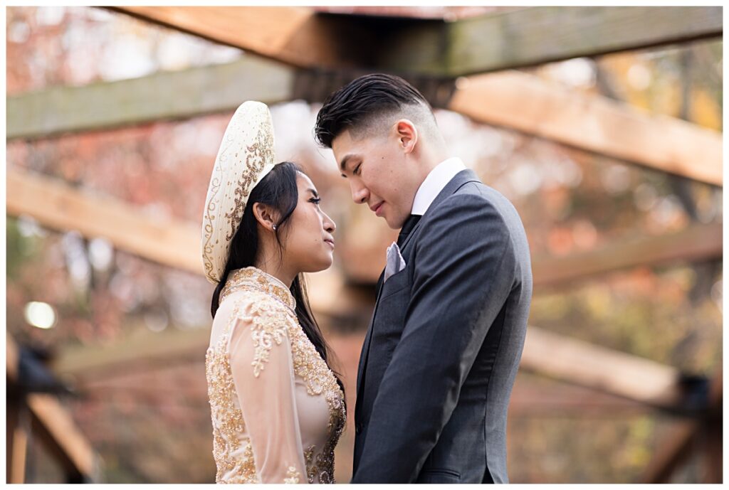 Vietnamese bride in yellow ao dai gazing at groom on bridge during Prairie creek portrait session photographed by Dallas wedding photographer Jenny Bui of Picture Bouquet Studio. 