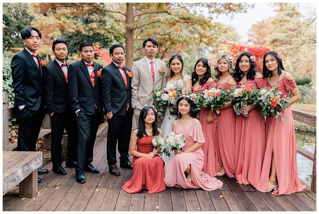 Bridal party in fall colors poses on wooden deck at Fort Worth Japanese Garden photographed by Jenny Bui of Picture Bouquet Studio. 