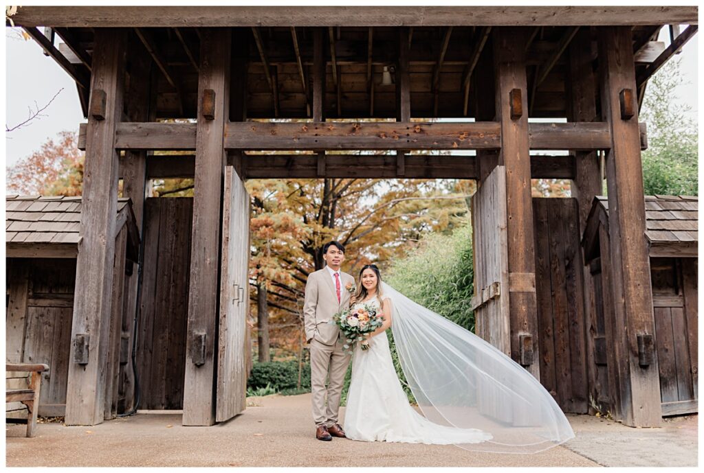 Beautiful shot of bride and groom in front wooden doors of Fort Worth Japanese Garden photographed by Jenny Bui of Picture Bouquet Studio. 