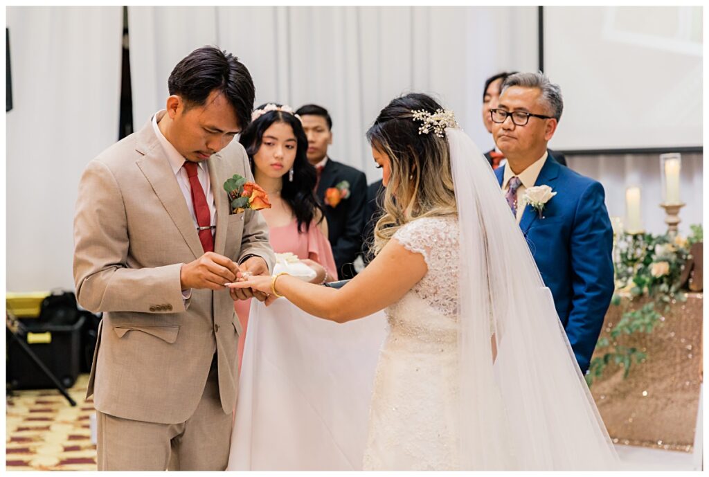 Groom placing ring on bride during ceremony  for The Pearl Wedding photographed by Picture Bouquet Studio. 