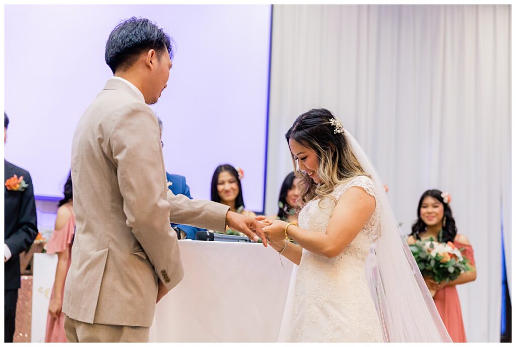 Bride placing ring on groom during ceremony  for The Pearl Wedding photographed by Picture Bouquet Studio. 