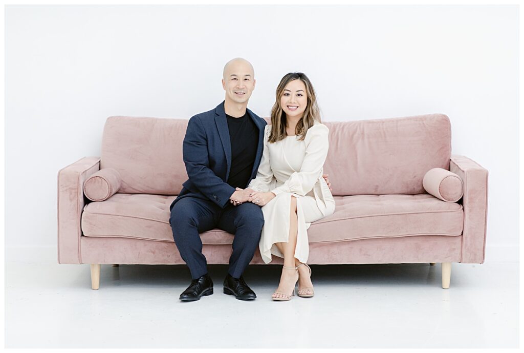Mommy and Daddy posing on light pink sofa at the Lumen Room during family session photographed by Picture Bouquet Studio. 