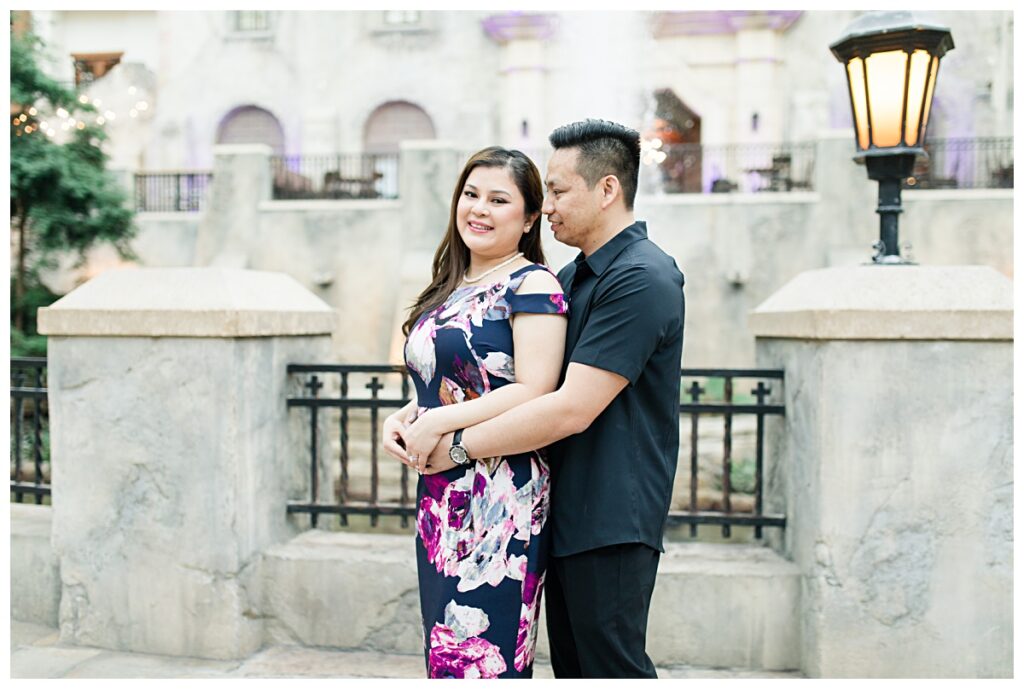 Guy hugging his fiancee in front of water fountain at Gaylord Texan Resort for Gaylord engagement session photographed by Picture Bouquet Studio. 