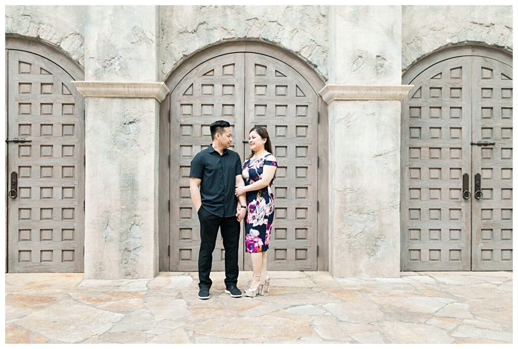 Engaged couple linking arms in front of castle door during Gaylord engagement session photographed by Dallas wedding photographer Jenny Bui of Picture Bouquet Studio. 