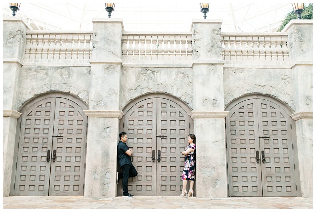 Guy and girl in face off in front of castle door at Gaylord Texan Resort for engagement session photographed by Dallas wedding photographer Jenny Bui of Picture Bouquet Studio. 