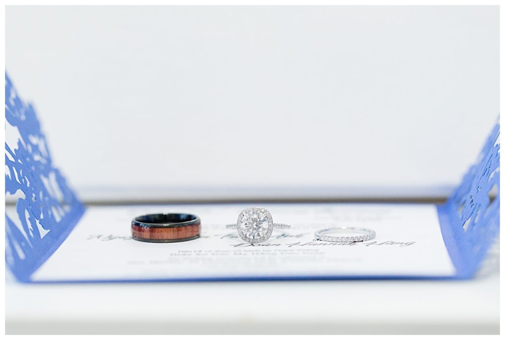 Ring shot on royal blue invitation for Dallas Vietnamese wedding photographed by Jenny Bui of Picture Bouquet Studio. 