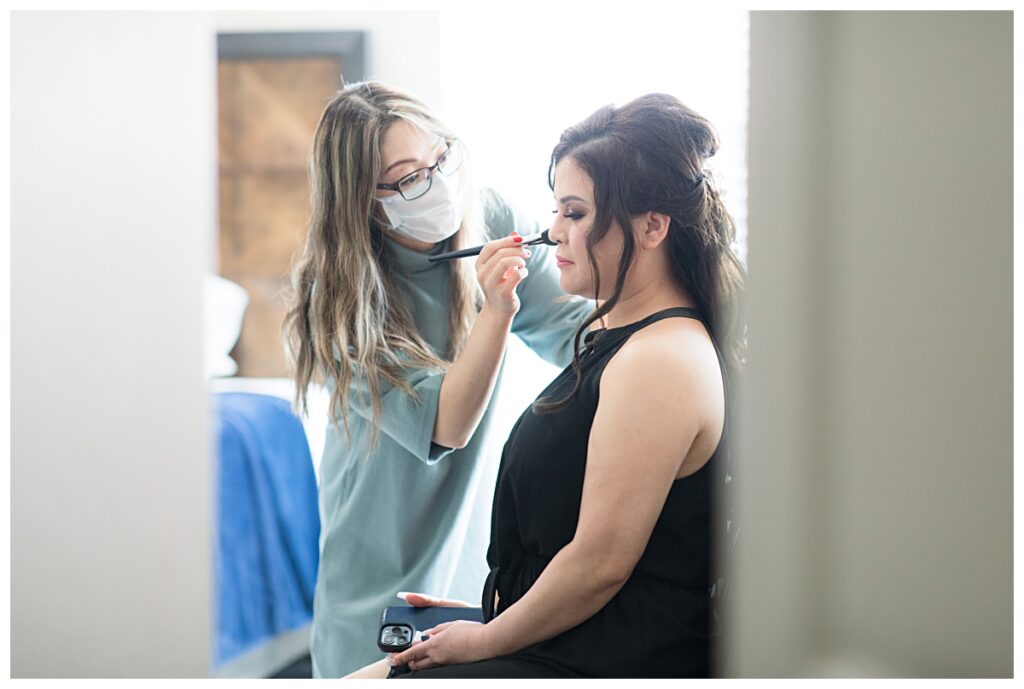 Makeup artist applying the finishing touch on bride for Dallas Vietnamese wedding photographed by Jenny Bui of Picture Bouquet Studio. 