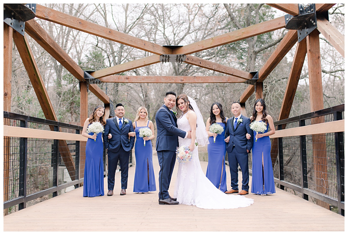 Royal blue bridal party poses on bridge at Prairie Creek Park in Richardson, TX for Dallas Vietnamese wedding photographed by Jenny Bui of Picture Bouquet Studio. 