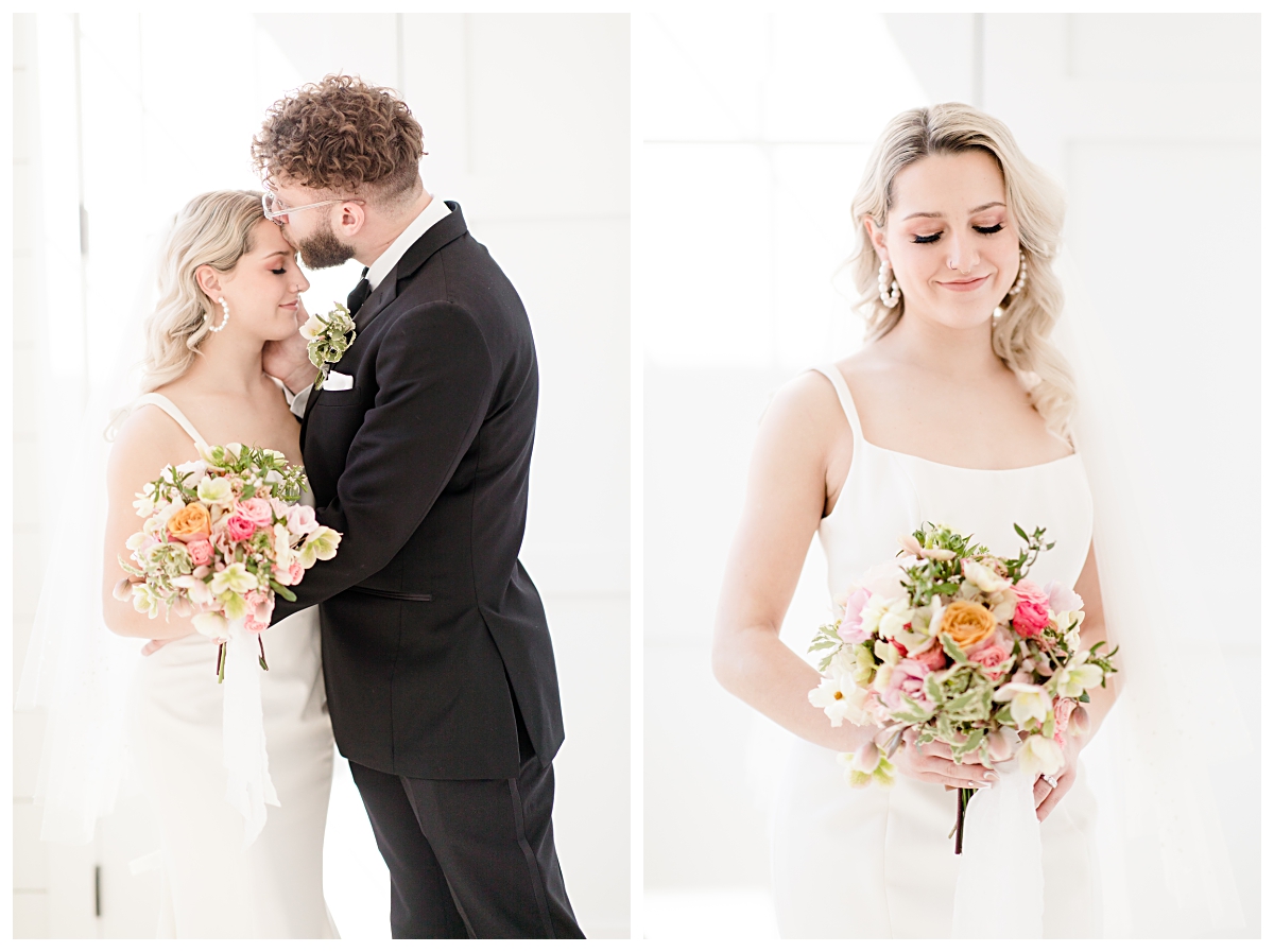 Groom kissing bride forehead on left and bride looking down at gorgeous spring colored bouquet on right  in all white chapel at The Gardenia Venue photographed by Jenny Bui of Picture Bouquet Studio.