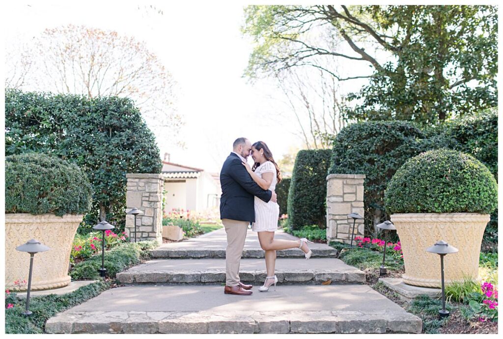 Engaged couple arm in arm along walkway at the Dallas Arboretum for a Dallas spring engagement session photographed by Jenny Bui of Picture Bouquet Studio. 