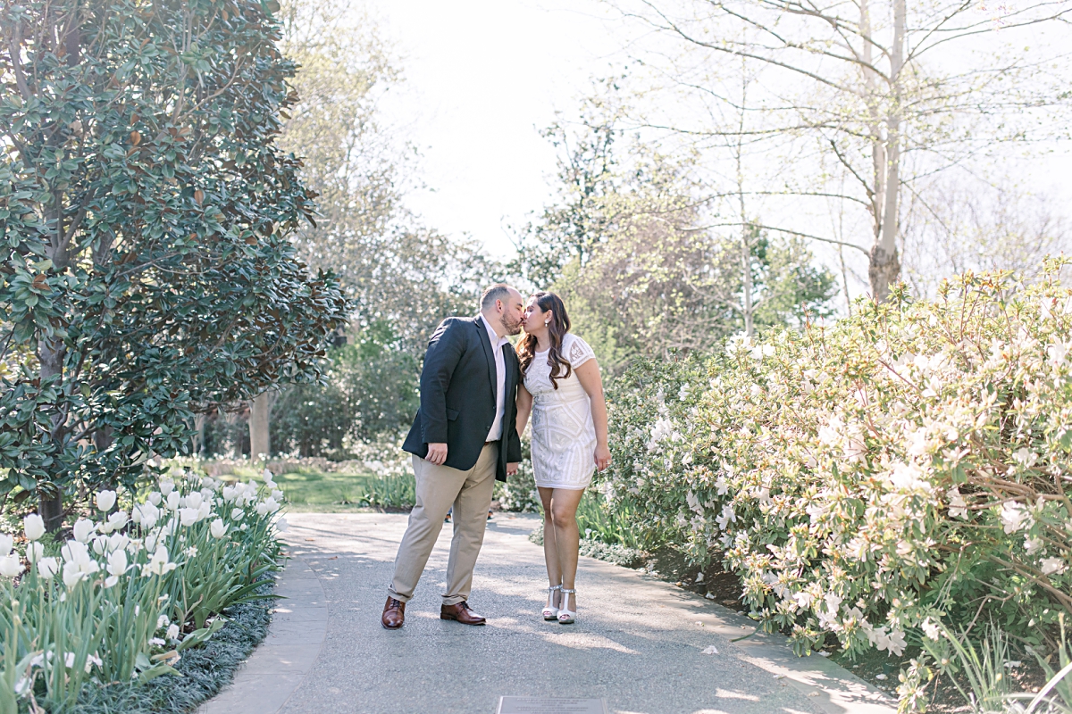 engaged couple leaning in for kiss at the Dallas Arboretum for their spring engagement session photographed by Jenny Bui of Picture Bouquet Studio.