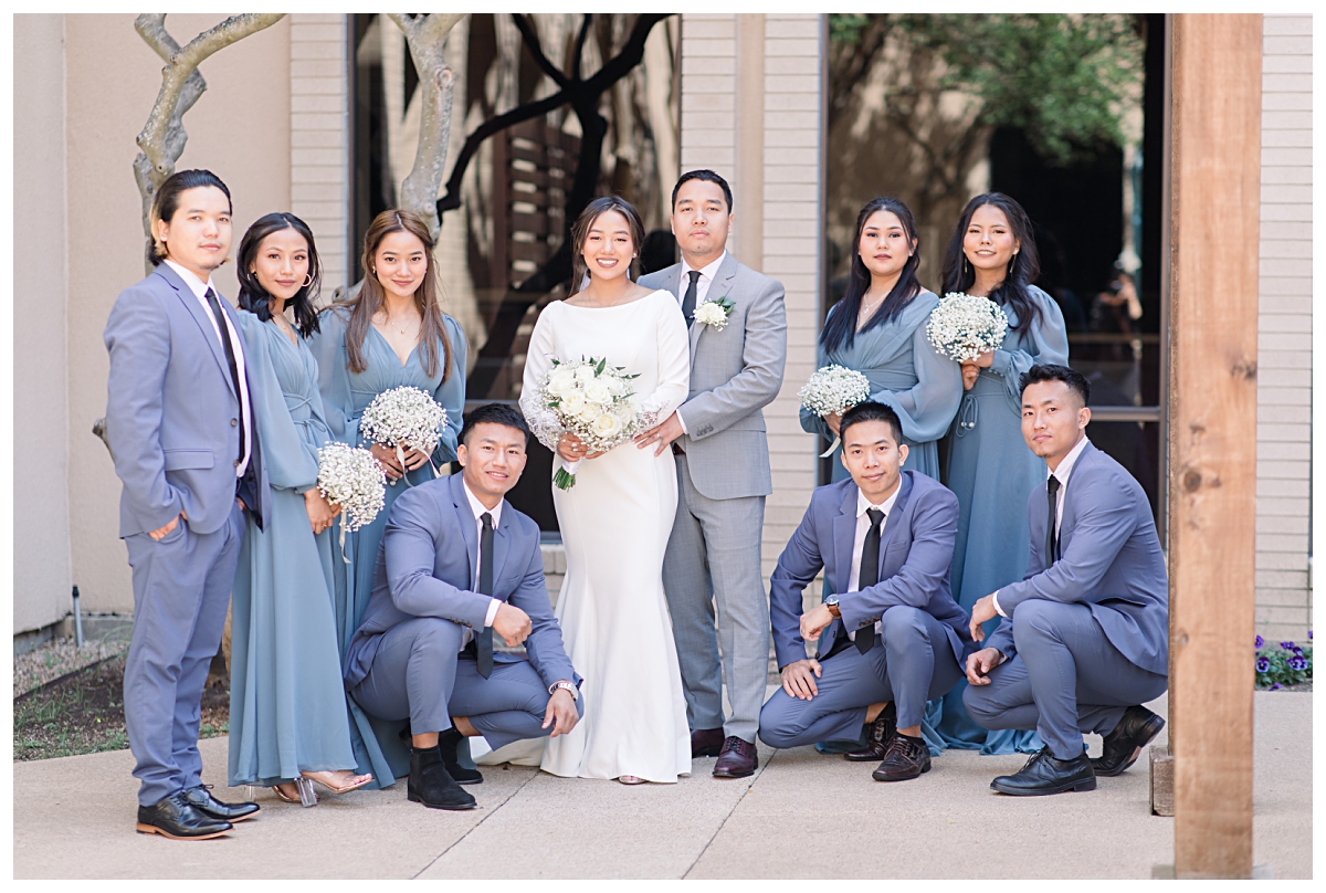 Bridal party in soft blue color palette smiling at camera during wedding day at Highland Oaks Church of Christ from a Dallas Asian wedding photographed by Jenny Bui of Picture Bouquet Studio. 