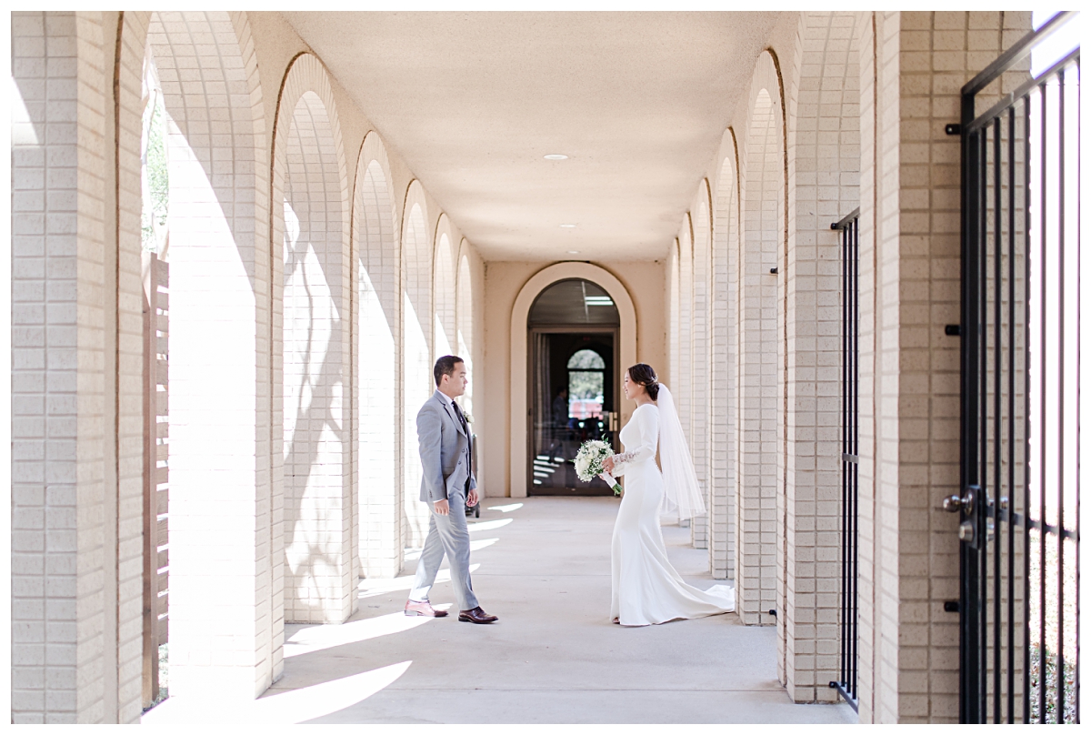 Bride and groom walking towards one another in the outside corridor of Highland Oaks Church of Christ from a Dallas Asian wedding photographed by Jenny Bui of Picture Bouquet Studio. 
