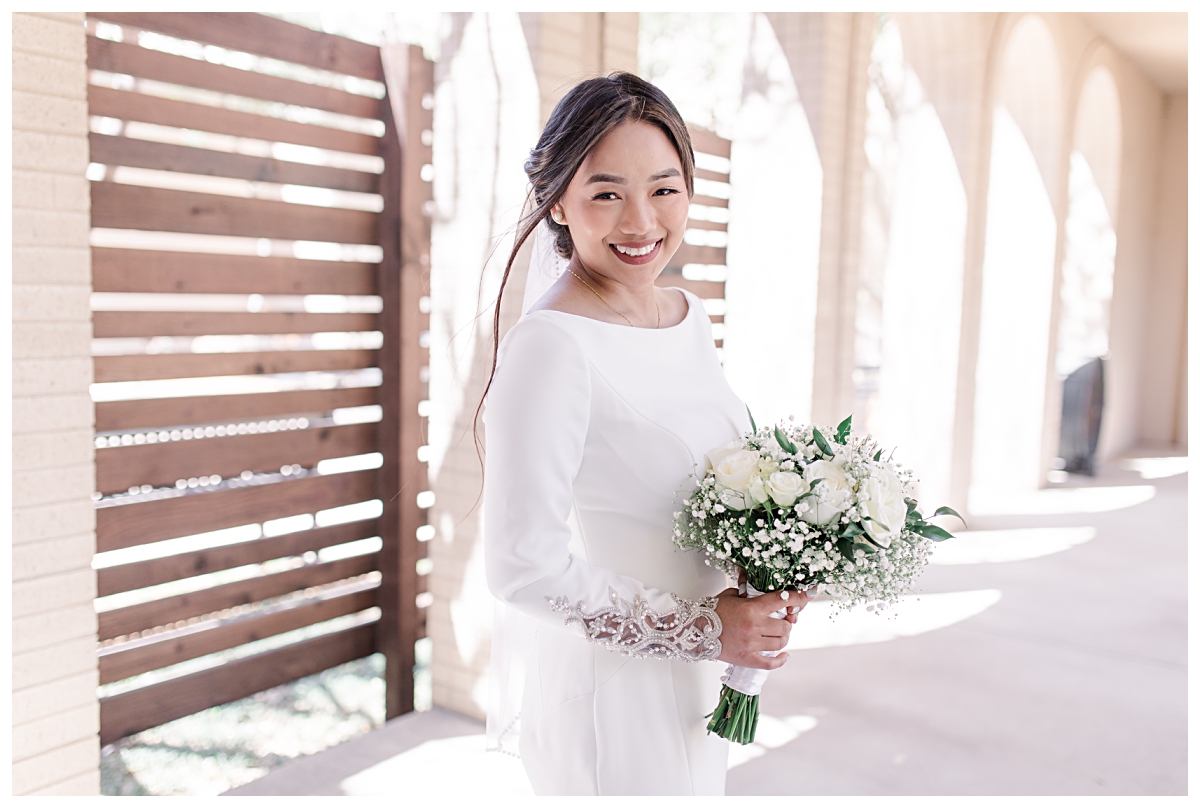 Gorgeous bride smiling at camera and holding her white roses and baby's breath bouquet from a Dallas Asian wedding photographed by Jenny Bui of Picture Bouquet Studio. 