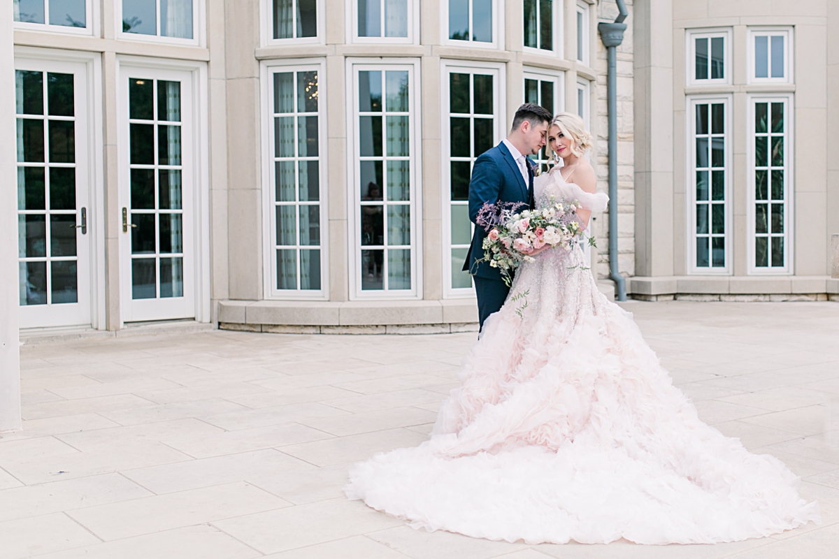 Groom in navy suit presses forehead to bride in blush wedding gown outside of The Olana wedding venue photographed by Dallas Wedding photographer Jenny Bui of Picture Bouquet Studio. 