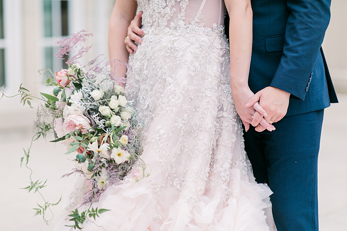 Close up of bouquet and bride in blush wedding dress holding hands with groom in navy blue suit at The Olana wedding venue photographed by Dallas Wedding photographer Jenny Bui of Picture Bouquet Studio. 
