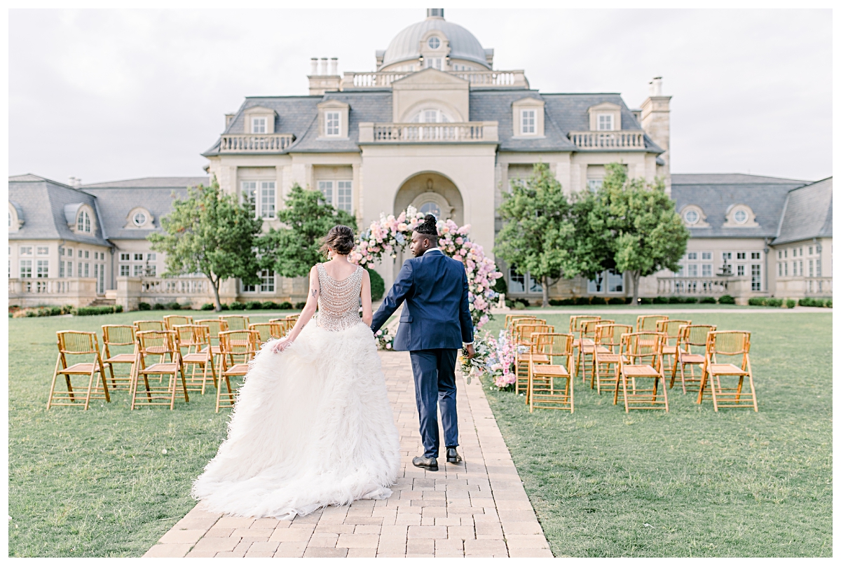 Groom in navy suit leading bride in vintage beaded and feathered gown down aisle at The Olana Wedding venue for styled shoot photographed by Dallas Wedding Photographer Jenny Bui of Picture Bouquet Studio. 