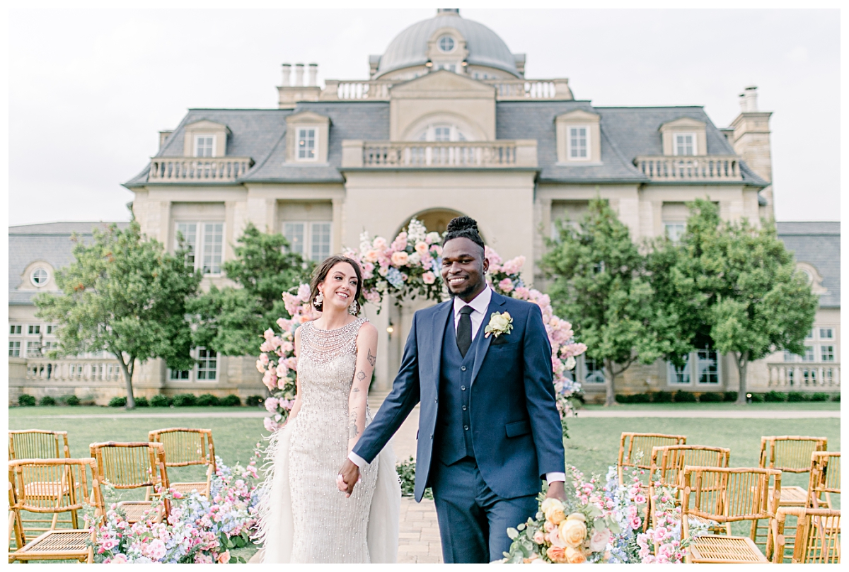 Groom in navy suit guiding bride down aisle on front lawn at The Olana Wedding venue for styled shoot photographed by Dallas Wedding Photographer Jenny Bui of Picture Bouquet Studio. 