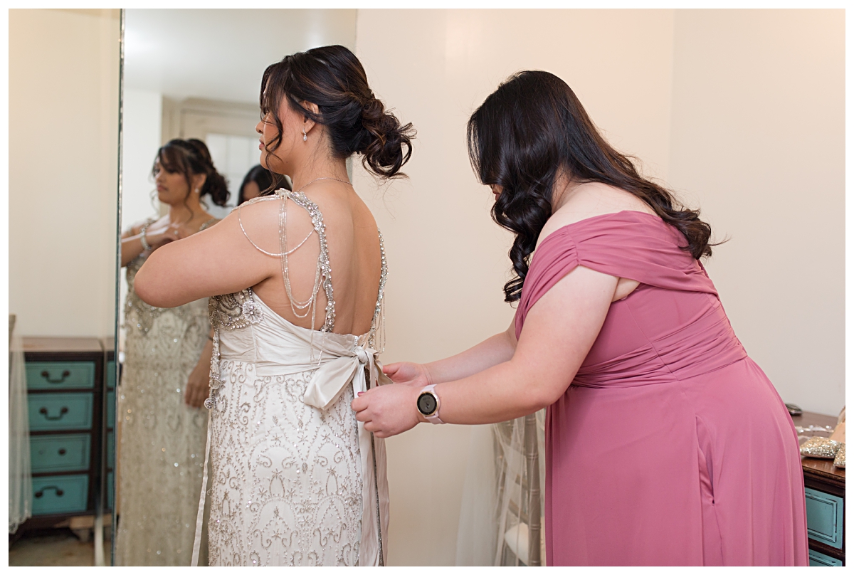 Maid of honor in dusty rose bridemaid's gown put finishing touches on bride at Zander House wedding photographed by Dallas wedding photographer Jenny Bui of Picture Bouquet Studio. 