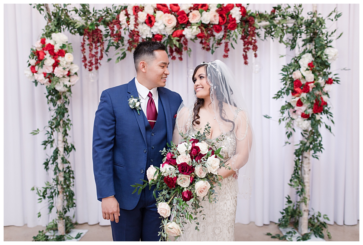 Bride in vintage beaded wedding dress gazing at groom in navy suit with burgundy tie at Zander House wedding photographed by Dallas wedding photographer Jenny Bui of Picture Bouquet Studio. 