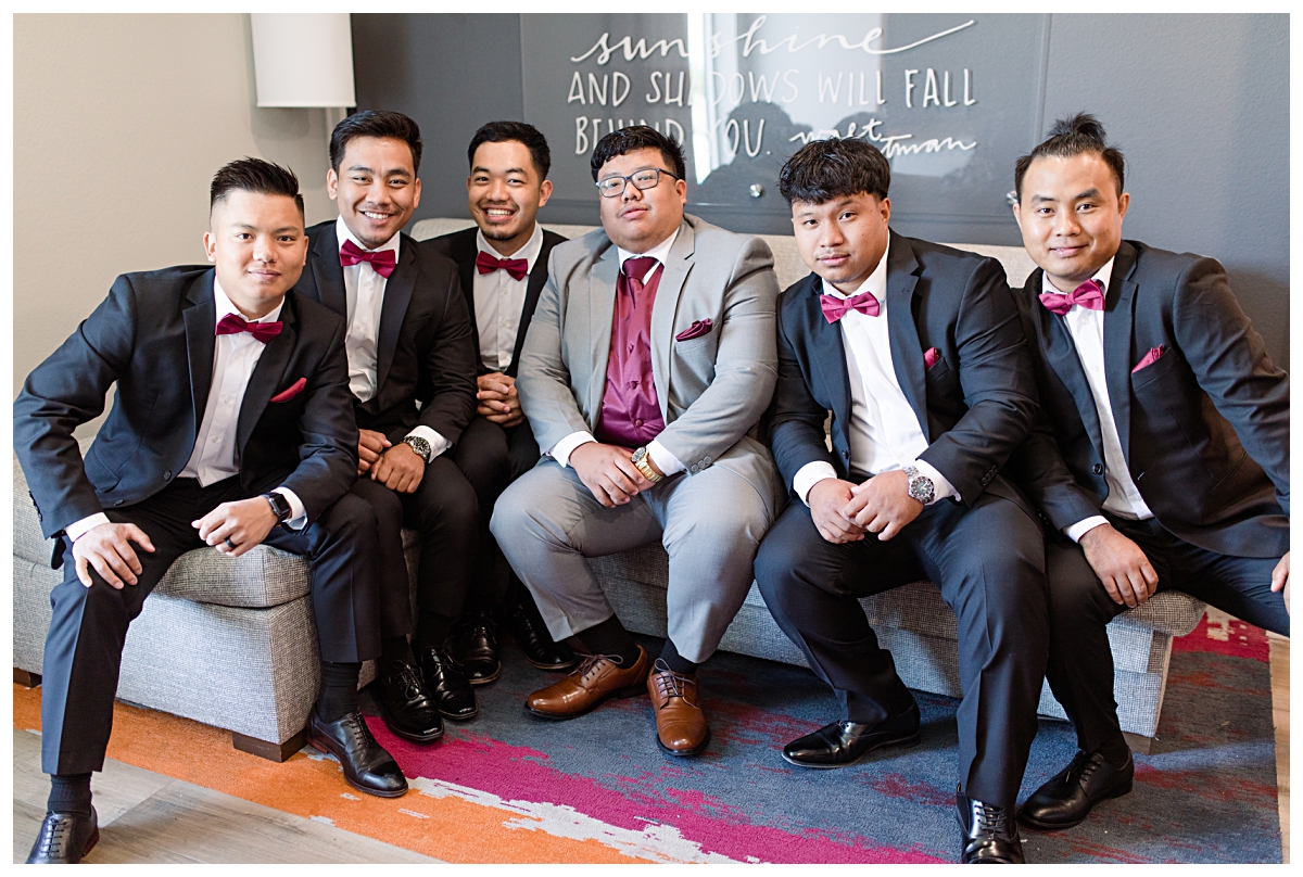 Groomsmen in burgundy bow-tie poses with groom for portraits during getting ready portion of wedding day photographed by Dallas wedding photographer Jenny Bui of Picture Bouquet Studio. 