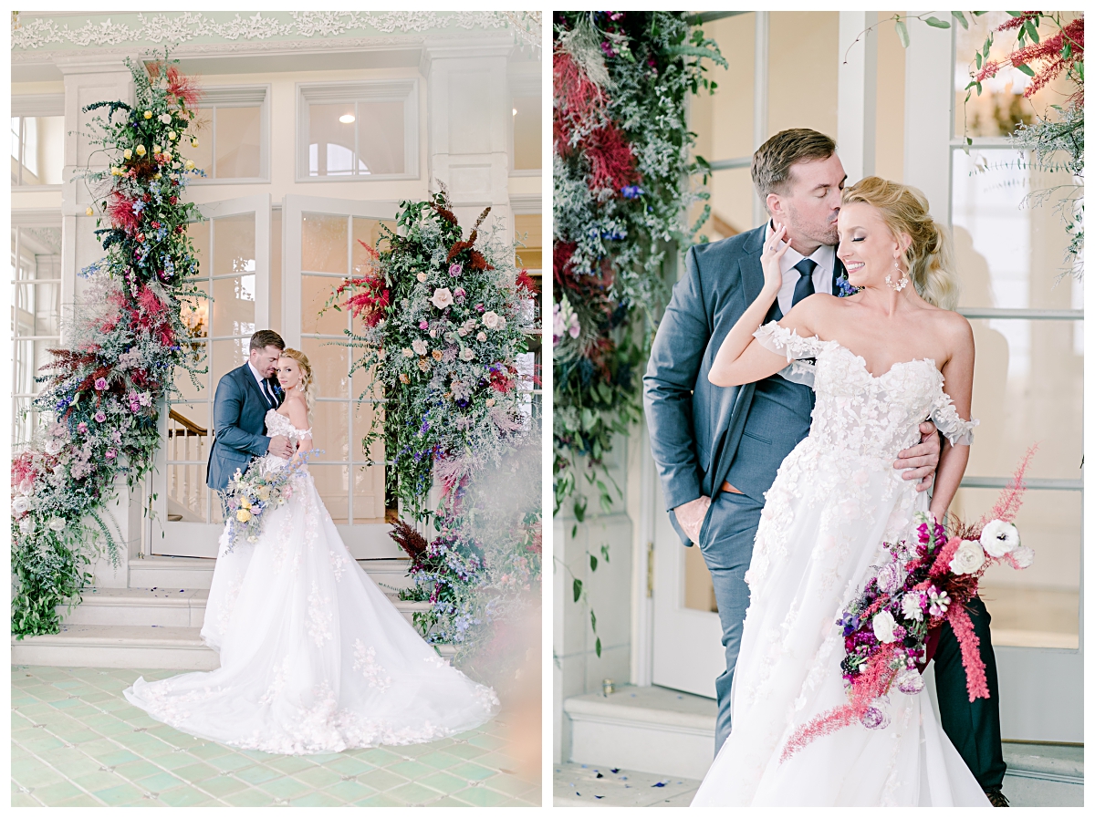 Bride in off shoulder white wedding dress hugging groom in front of floral arches in front of glass doorway at The Olana photographed by Dallas wedding photographer Jenny Bui of Picture Bouquet Studio. 
