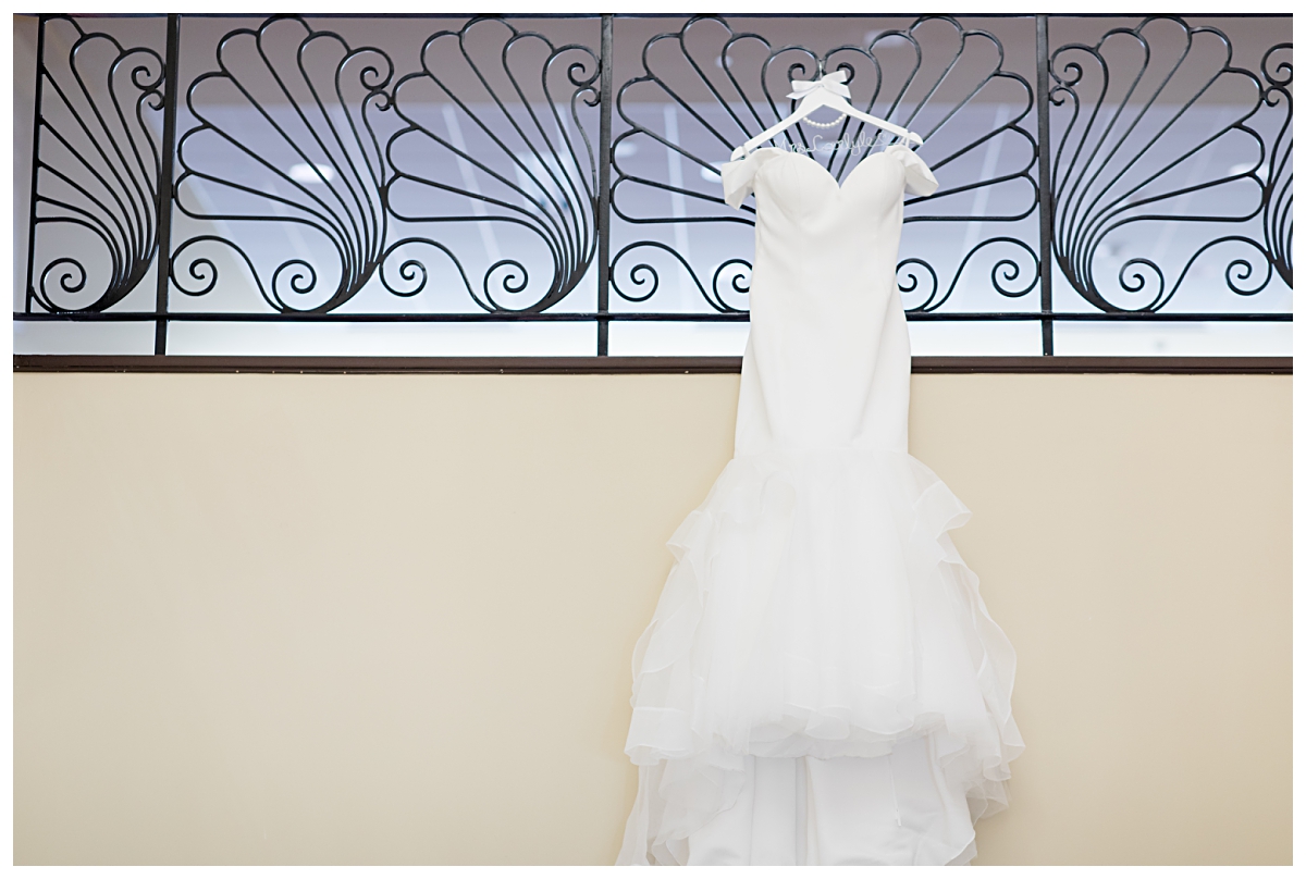 Wedding day dress hung on hotel staircase photographed by Dallas wedding photographer Jenny Bui of Picture Bouquet Studio for Holy Trinity Catholic Church wedding in Dallas, TX.  