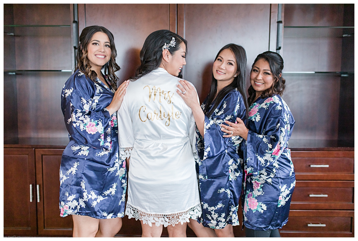 Bridesmaids in navy and floral robe showing off the bride's new last name on back of her robe photographed by Dallas wedding photographer Jenny Bui of Picture Bouquet Studio for Holy Trinity Catholic Church wedding in Dallas, TX.  