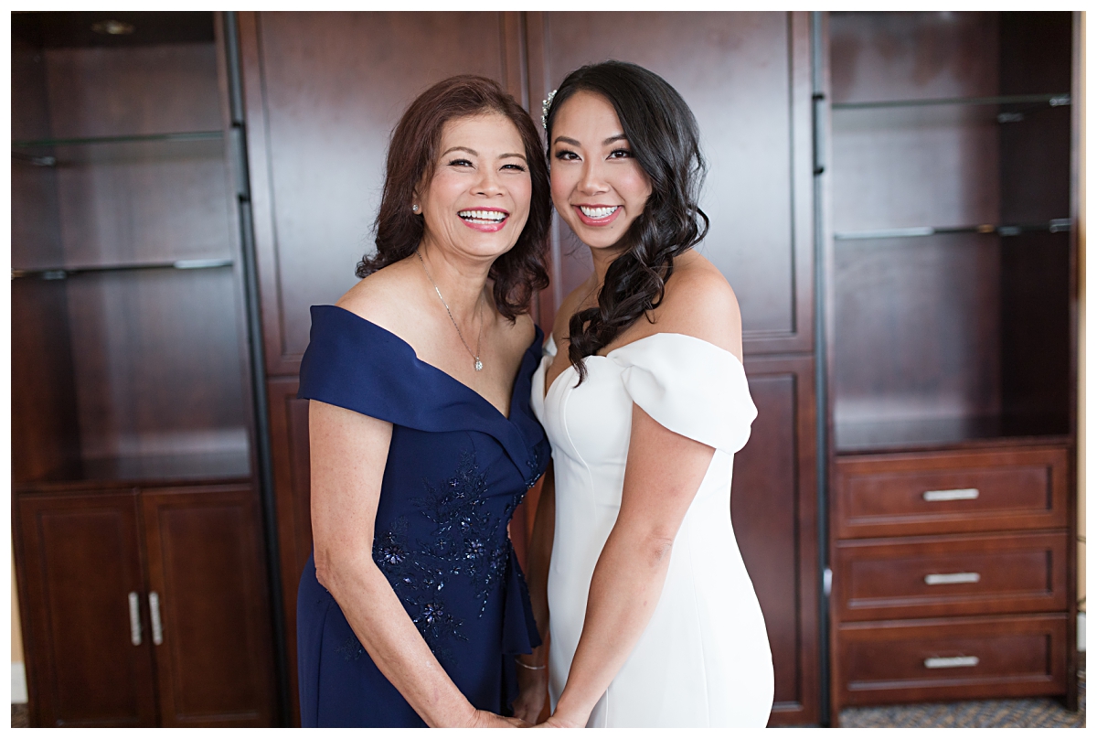 Gorgeous Asian bride and mother of the bride posing for camera during getting ready portion of the day photographed by Dallas wedding photographer Jenny Bui of Picture Bouquet Studio for Holy Trinity Catholic Church wedding in Dallas, TX.  