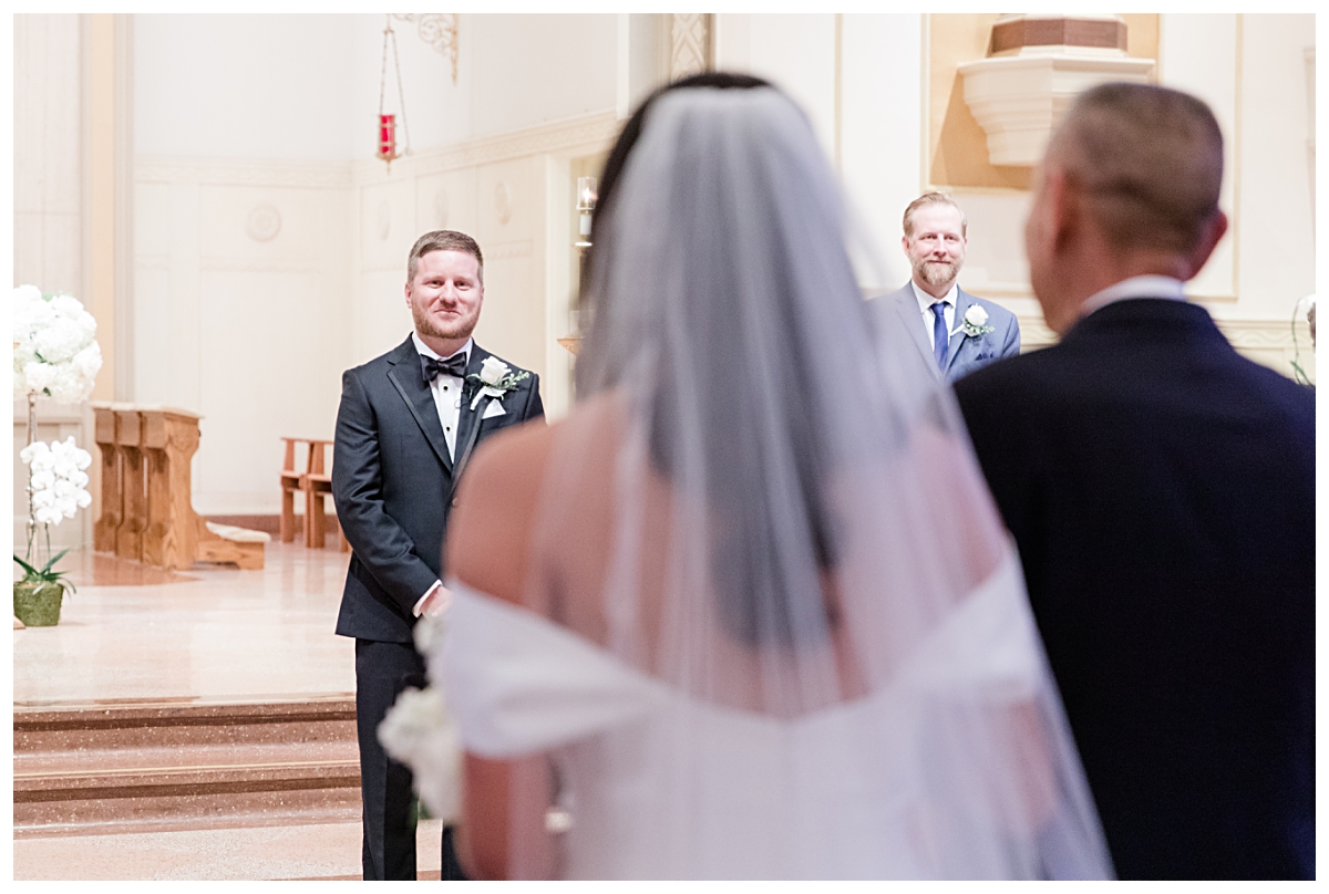 Groom gazing lovingly at bride as she gets up to him on aisle photographed by Dallas wedding photographer Jenny Bui of Picture Bouquet Studio for Holy Trinity Catholic Church wedding in Dallas, TX.  