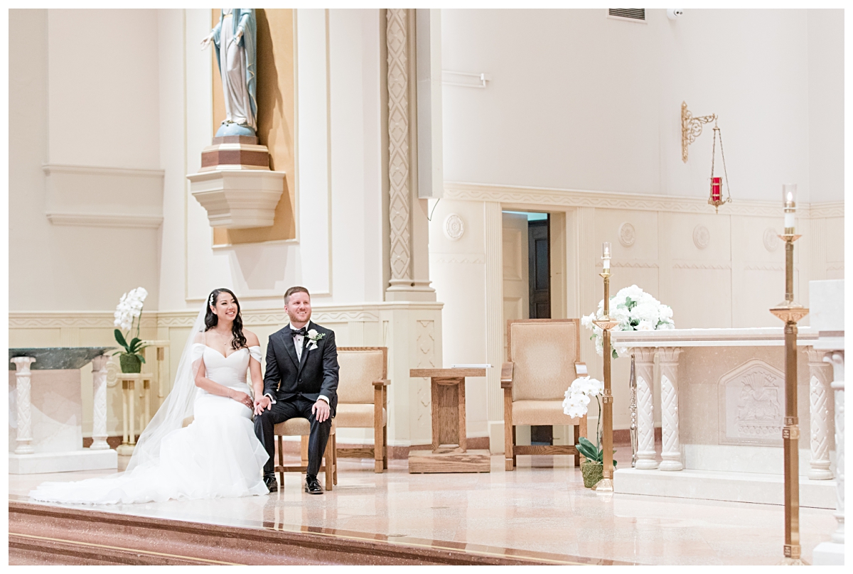 Bride and groom smiling as priest speaks photographed by Dallas wedding photographer Jenny Bui of Picture Bouquet Studio for Holy Trinity Catholic Church wedding in Dallas, TX.  