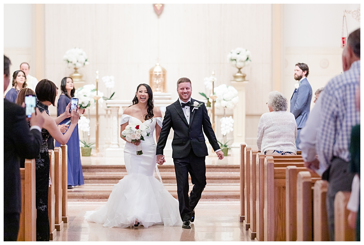 Joyful bride and groom walking down aisle as husband and wife after ceremony photographed by Dallas wedding photographer Jenny Bui of Picture Bouquet Studio for Holy Trinity Catholic Church wedding in Dallas, TX.  