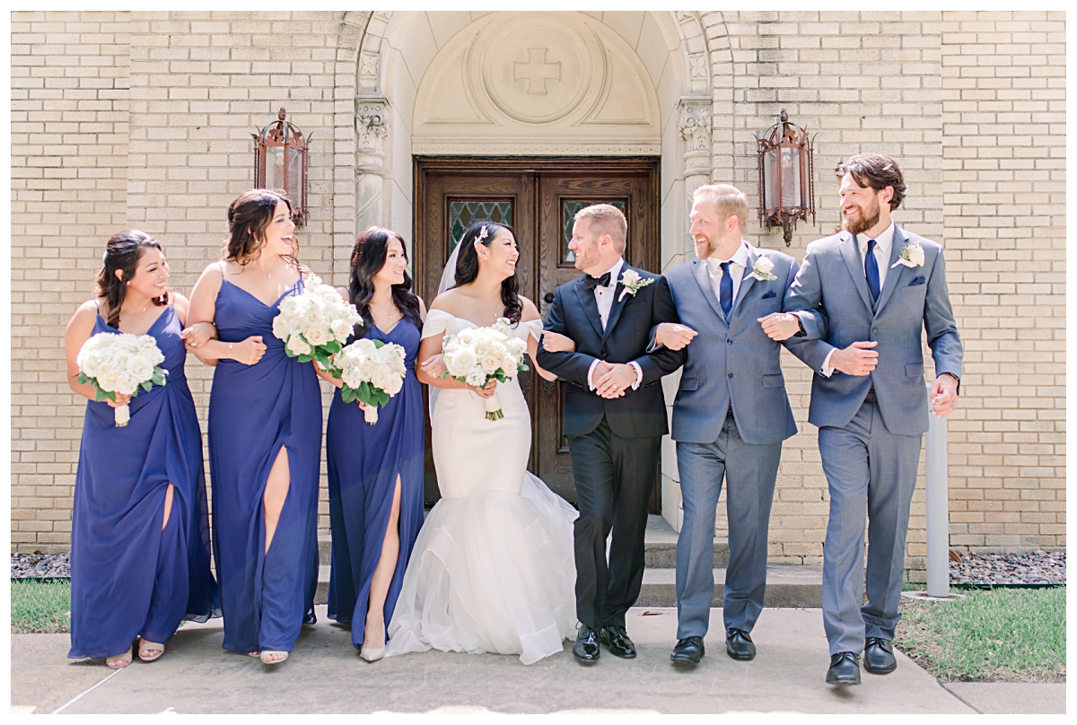 Royal blue and grey bridal party walking and talking happily towards camera photographed by Dallas wedding photographer Jenny Bui of Picture Bouquet Studio for Holy Trinity Catholic Church wedding in Dallas, TX.  