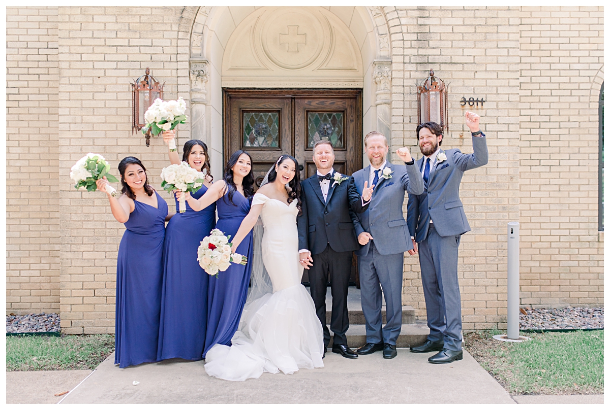 Royal blue and grey bridal party cheers for camera photographed by Dallas wedding photographer Jenny Bui of Picture Bouquet Studio for Holy Trinity Catholic Church wedding in Dallas, TX.  