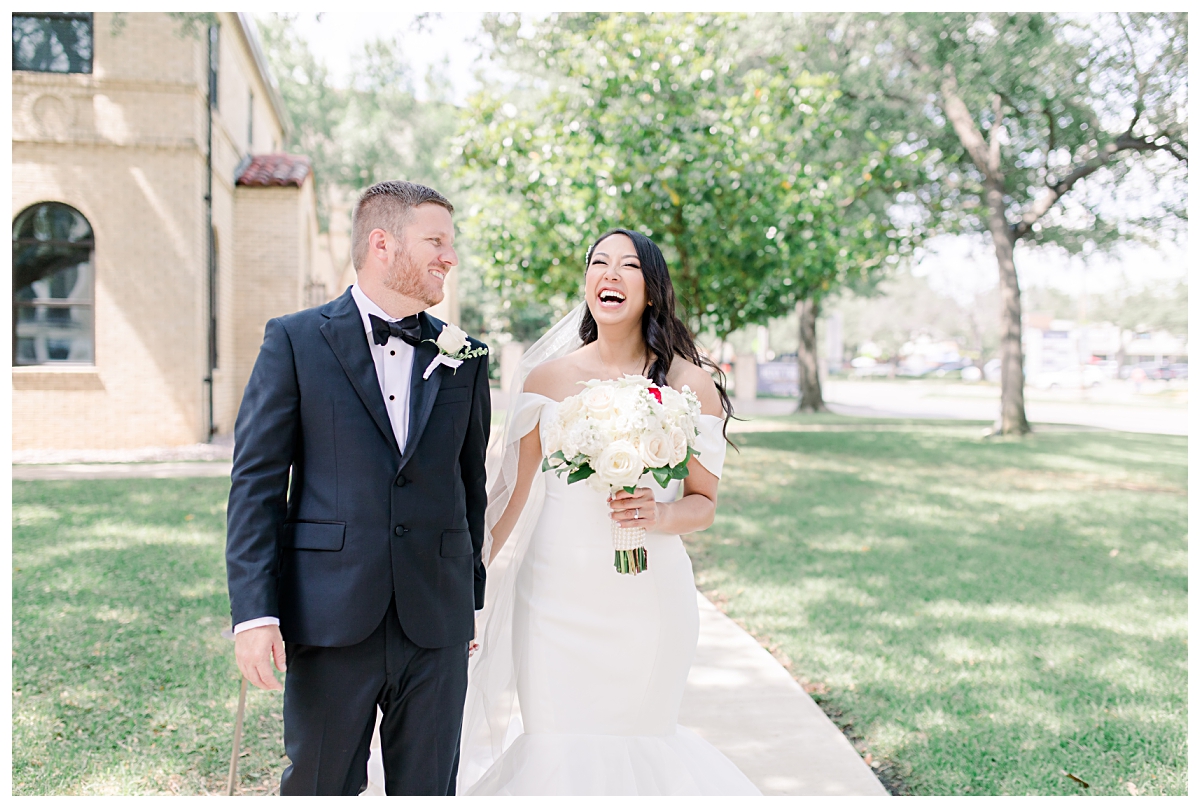 Joyful bride laughing and walking with her new husband in courtyard photographed by Dallas wedding photographer Jenny Bui of Picture Bouquet Studio for Holy Trinity Catholic Church wedding in Dallas, TX.  