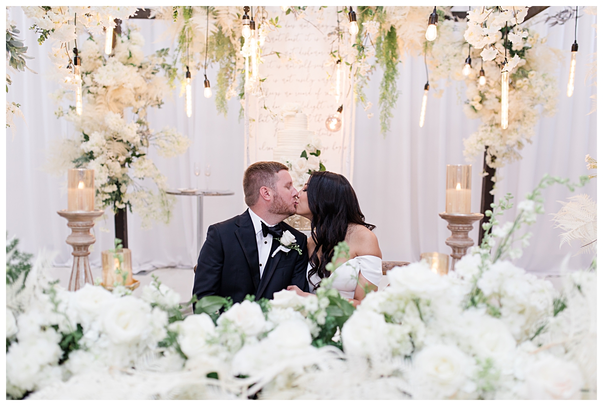 Bride and groom shares a kiss in the center of all the wedding reception decoration photographed by Dallas wedding photographer Jenny Bui of Picture Bouquet Studio for The Pearl  wedding in Dallas, TX.   