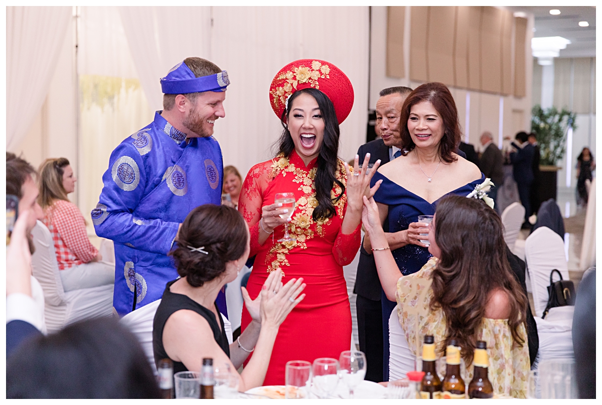Gorgeous bride in traditional Vietnamese ao dai shows off wedding ring during table greetings photographed by Dallas wedding photographer Jenny Bui of Picture Bouquet Studio for The Pearl  wedding in Dallas, TX.   